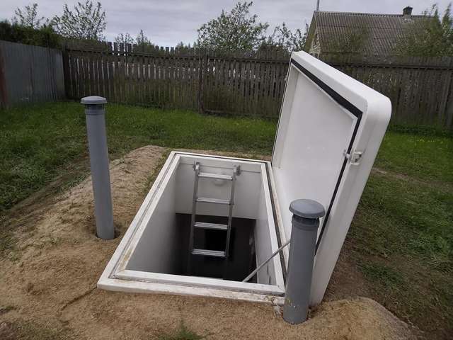 Открытый люк погреба на участке после монтажа