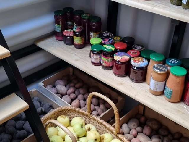 Внутри погреба: полки с заготовками и урожаем
